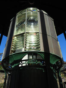 Fresnel lens emphasizing the curved glass panels and the base in shadow.,